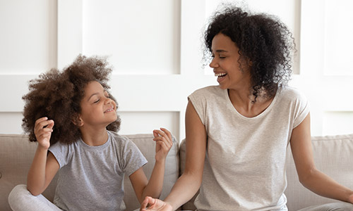 Woman and girl sitting on the couch meditating.