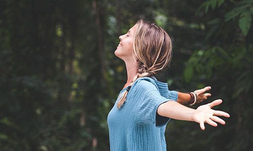 Woman outside with her arms outstretched behind her.